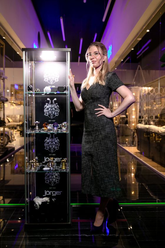 Julia Grekova next to a glass showcase with valuable, decorative bathroom fittings handles by Jörger.